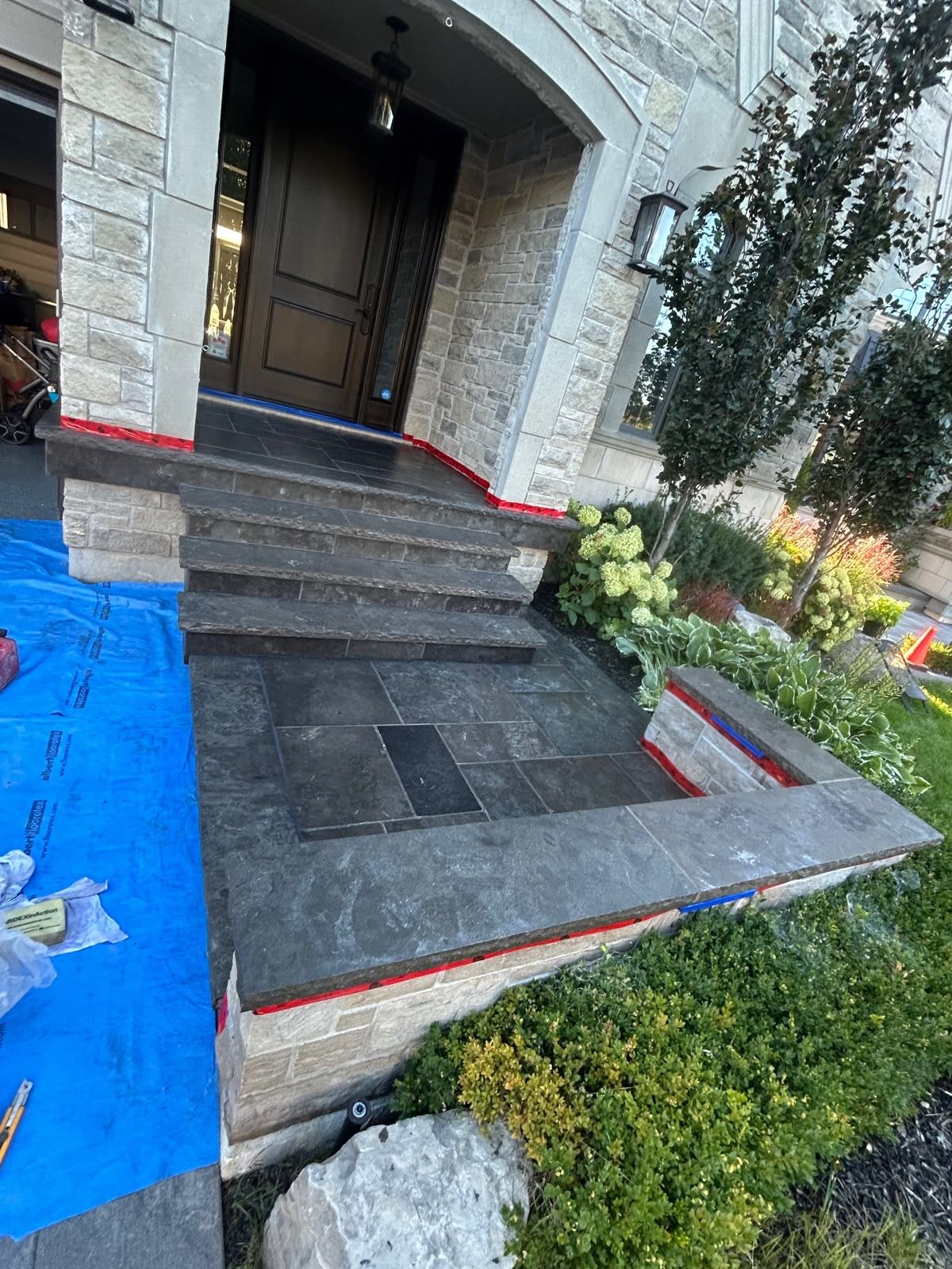 Dark sealed natural-stone entrance landing with masking still in place