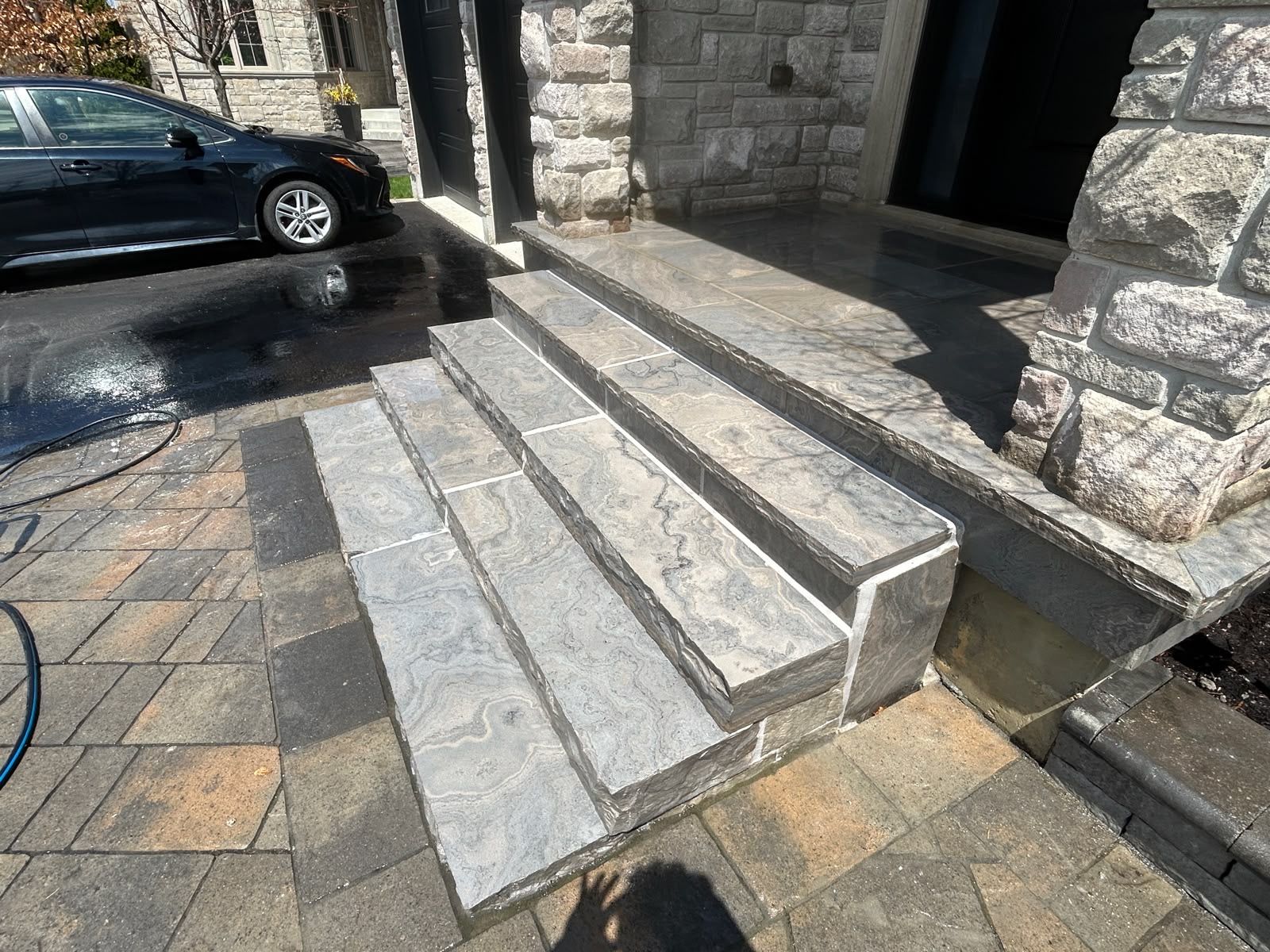 Natural-stone walkway and steps beside a driveway during surface washing